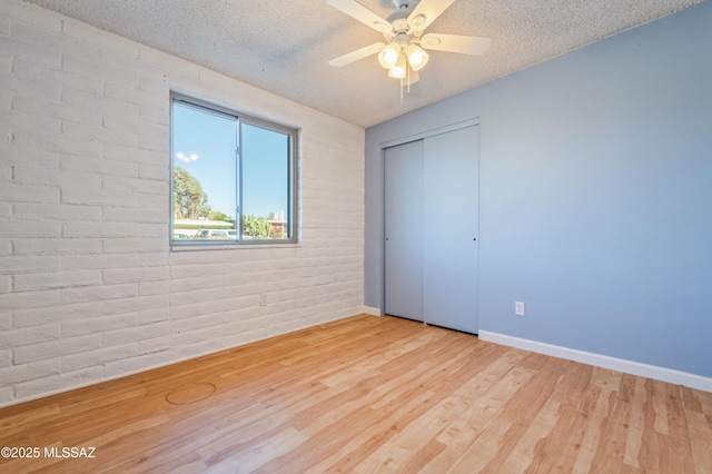 unfurnished bedroom featuring a closet, a textured ceiling, baseboards, and wood finished floors