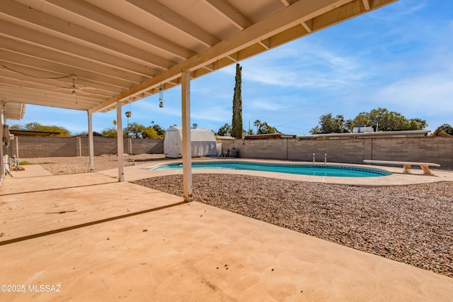 view of swimming pool featuring a shed, an outdoor structure, a fenced backyard, and a patio