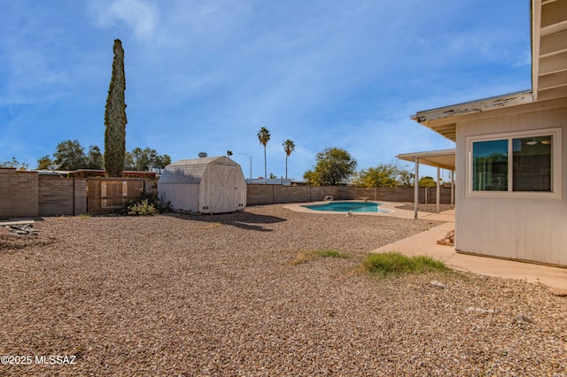 view of yard with an outbuilding, a fenced backyard, a patio, and a shed