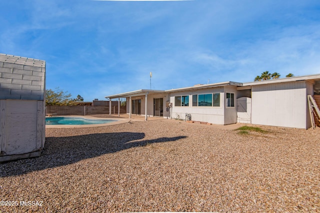 back of property featuring a fenced backyard, a fenced in pool, and a patio