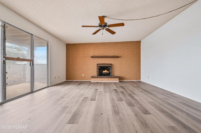 unfurnished living room with baseboards, a ceiling fan, wood finished floors, a textured ceiling, and a fireplace