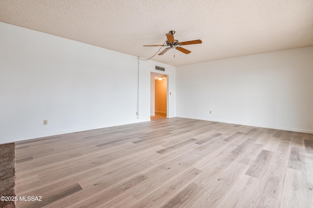 empty room featuring light wood-style flooring, visible vents, ceiling fan, and a textured ceiling