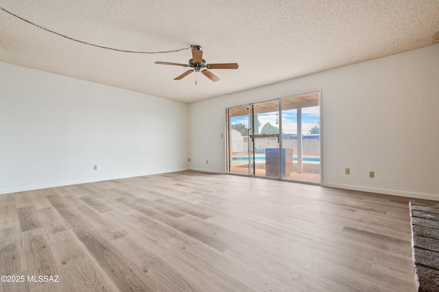 empty room with a textured ceiling, baseboards, a ceiling fan, and light wood-style floors