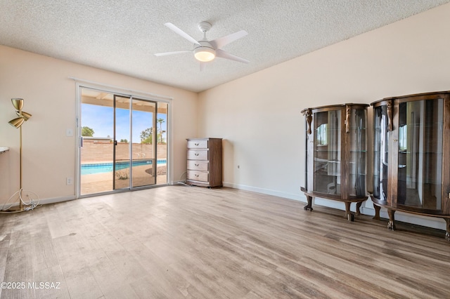 spare room with baseboards, a textured ceiling, a ceiling fan, and wood finished floors