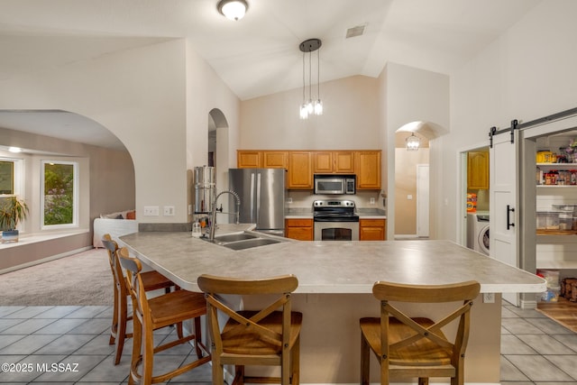 10117 E Sky Castle Way, Tucson, AZ 85730 - kitchen with a kitchen breakfast bar, washer / clothes dryer, arched walkways, a peninsula, and appliances with stainless steel finishes