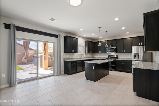 kitchen with light stone countertops, recessed lighting, a sink, stainless steel appliances, and a center island