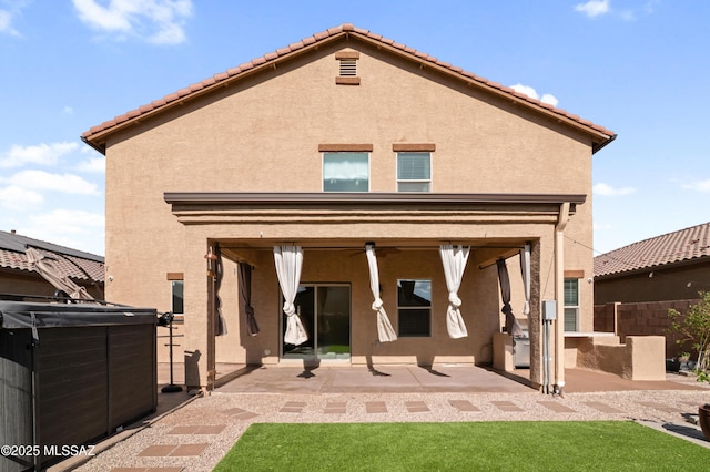 back of property with stucco siding, fence, a hot tub, and a patio area