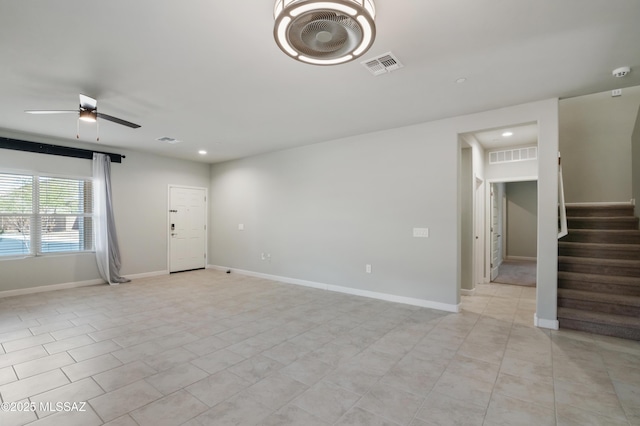 unfurnished living room with visible vents, baseboards, and stairway