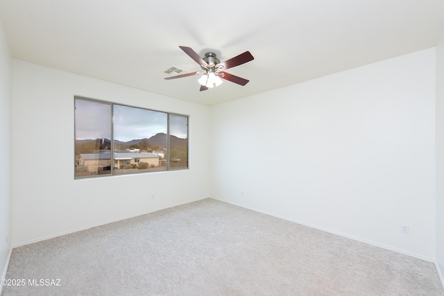 empty room with ceiling fan, carpet floors, visible vents, and baseboards