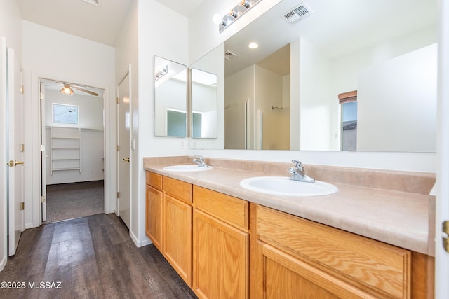 full bathroom with double vanity, visible vents, a sink, and wood finished floors