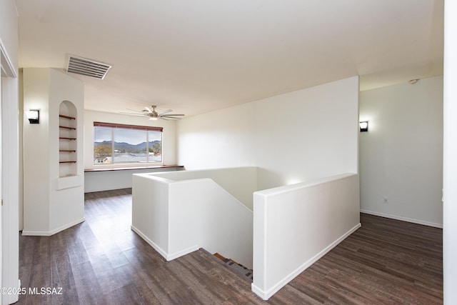 hall featuring baseboards, visible vents, dark wood finished floors, and an upstairs landing