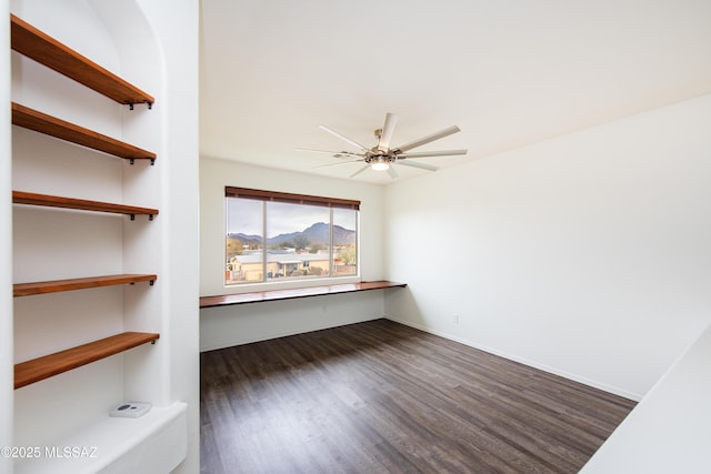 empty room with dark wood finished floors, a ceiling fan, and baseboards