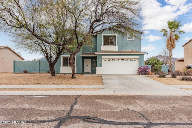 traditional-style house featuring a garage, driveway, fence, and stucco siding