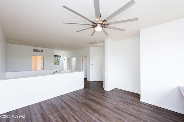 empty room with dark wood-type flooring, visible vents, ceiling fan, and baseboards