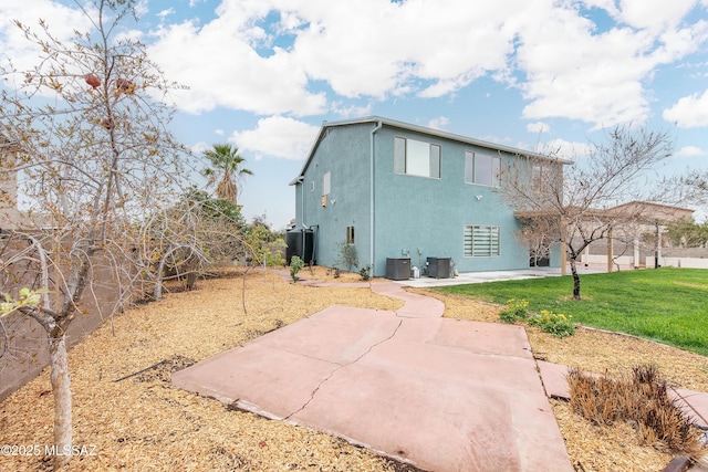 rear view of property featuring central air condition unit, a yard, a patio, and stucco siding