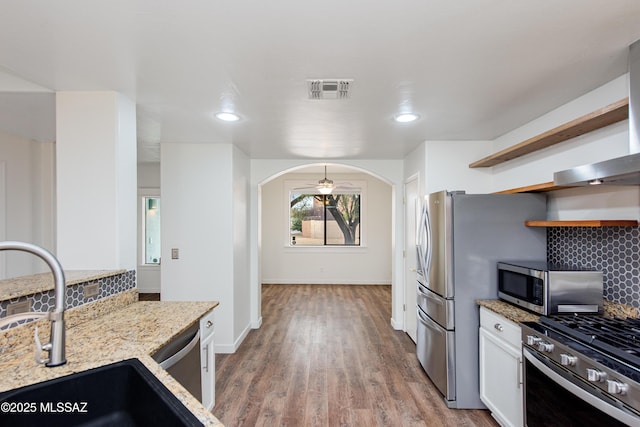 kitchen featuring appliances with stainless steel finishes, arched walkways, visible vents, and tasteful backsplash