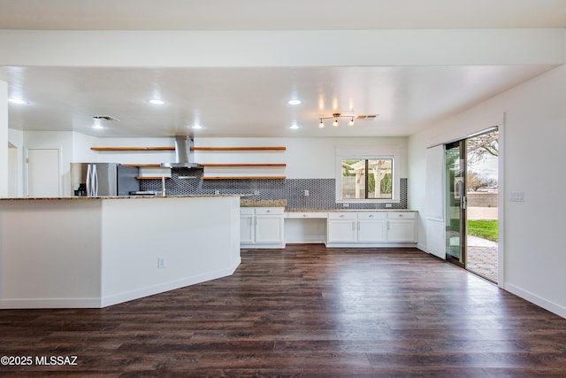 kitchen featuring dark wood-style flooring, built in study area, stainless steel fridge with ice dispenser, and exhaust hood