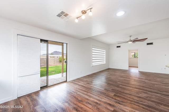 unfurnished room featuring a wealth of natural light, dark wood-style flooring, and visible vents