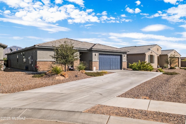 view of front facade with a tile roof, brick siding, stucco siding, an attached garage, and driveway