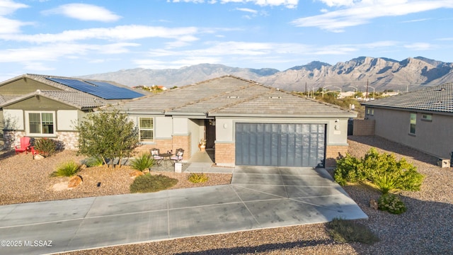 view of front of house featuring an attached garage, driveway, a mountain view, and a tiled roof