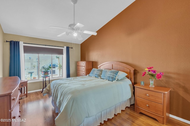 bedroom featuring ceiling fan, wood finished floors, baseboards, and vaulted ceiling