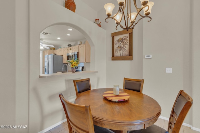 dining room featuring a ceiling fan, visible vents, baseboards, light tile patterned flooring, and arched walkways