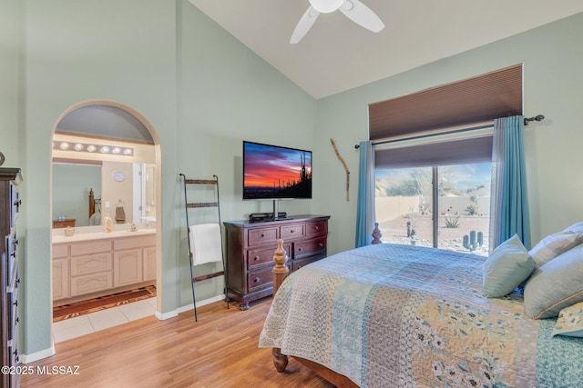 bedroom with a ceiling fan, ensuite bathroom, arched walkways, light wood finished floors, and lofted ceiling