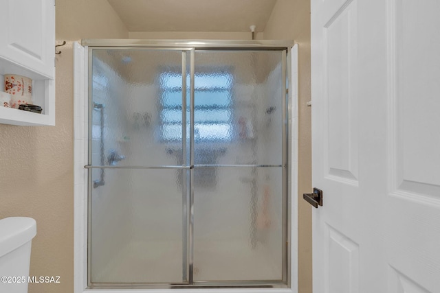 bathroom with a shower stall and toilet