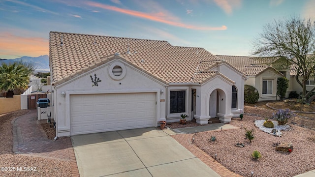 mediterranean / spanish-style house with a tile roof, stucco siding, concrete driveway, and a garage