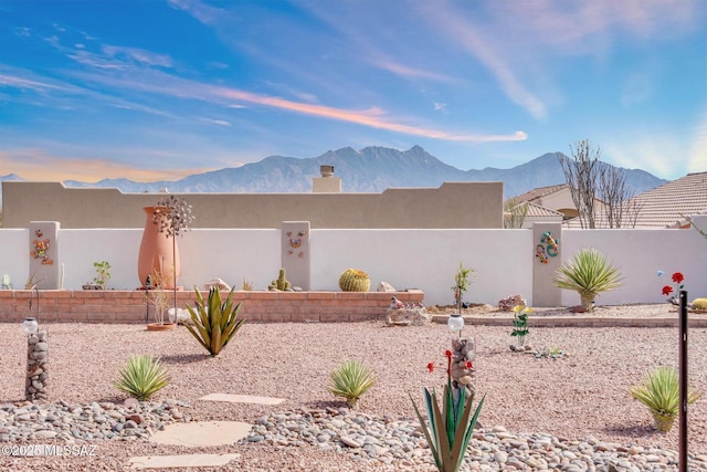 view of front of home with stucco siding, a fenced front yard, and a mountain view