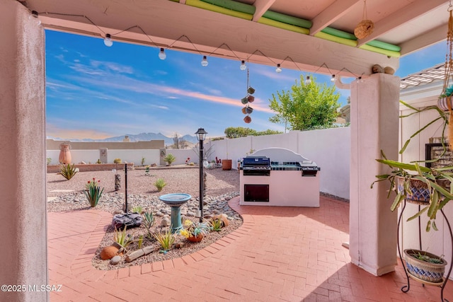 view of patio / terrace with exterior kitchen, a fenced backyard, and a mountain view