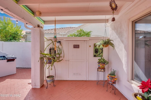 doorway to property featuring stucco siding, a tiled roof, and a patio