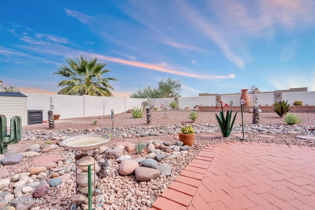 yard at dusk featuring a patio and a fenced backyard