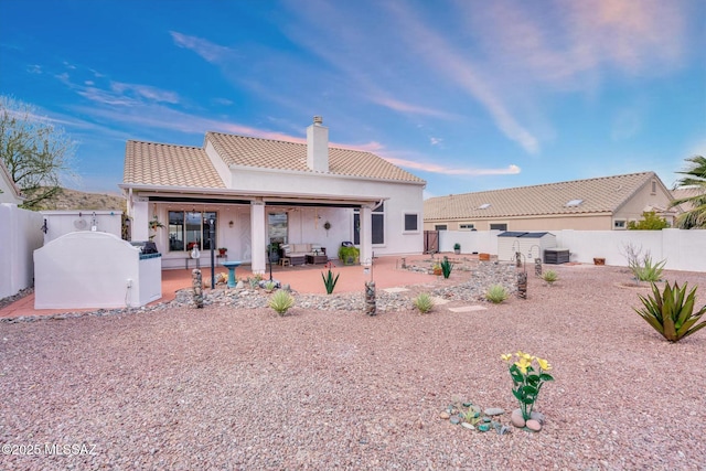 back of property featuring a patio, a fenced backyard, a chimney, and a tiled roof