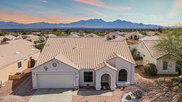 view of front of property featuring a mountain view, driveway, an attached garage, and a tile roof