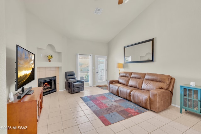 living room with visible vents, high vaulted ceiling, light tile patterned flooring, a fireplace, and baseboards