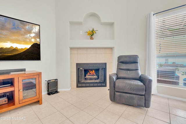 living area featuring tile patterned flooring, a tile fireplace, and baseboards