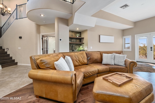 living room with visible vents, baseboards, stairs, french doors, and a notable chandelier