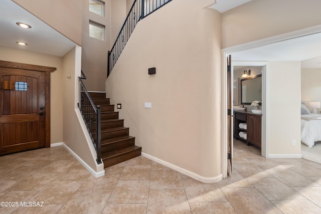 foyer with recessed lighting, stairway, baseboards, and a high ceiling