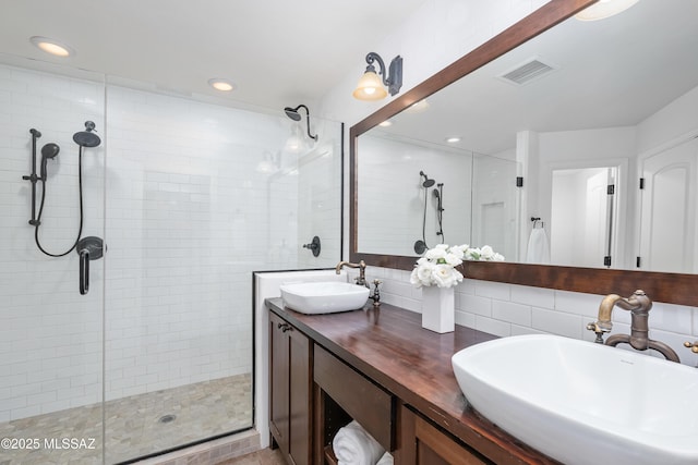 bathroom featuring a sink, visible vents, a stall shower, and double vanity