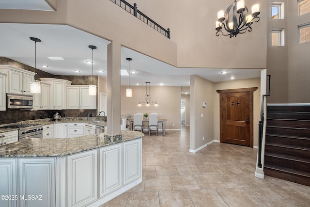 kitchen with backsplash, appliances with stainless steel finishes, baseboards, a chandelier, and light stone countertops