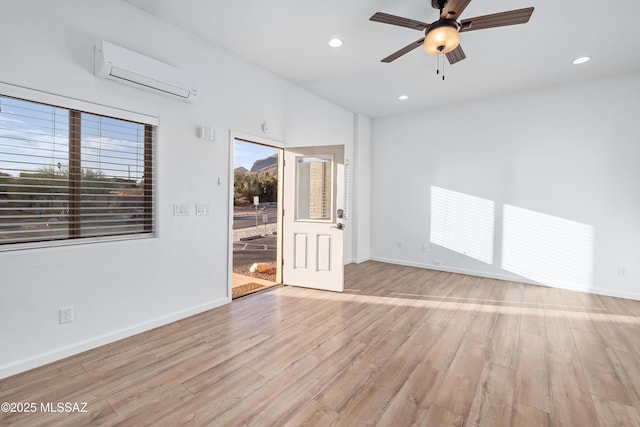 unfurnished room with recessed lighting, baseboards, light wood-style flooring, and a wall unit AC