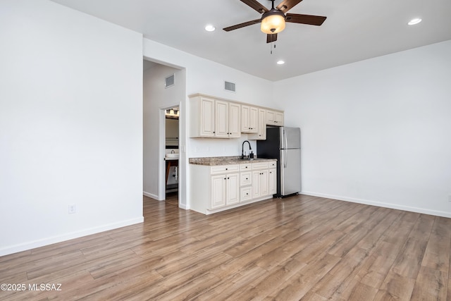 kitchen with a ceiling fan, visible vents, baseboards, light wood-style flooring, and freestanding refrigerator