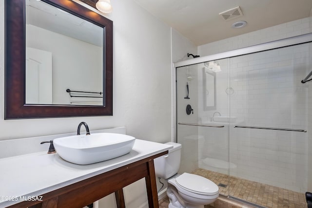 full bathroom featuring visible vents, a shower stall, toilet, and vanity