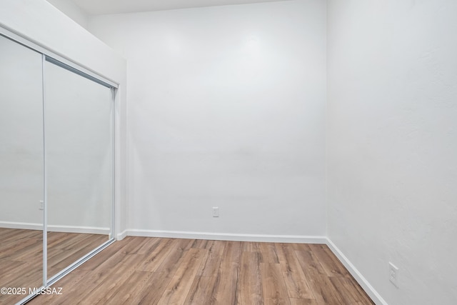 unfurnished bedroom featuring a closet, baseboards, and wood finished floors