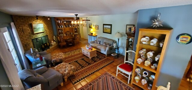 tiled living area with ceiling fan and a brick fireplace