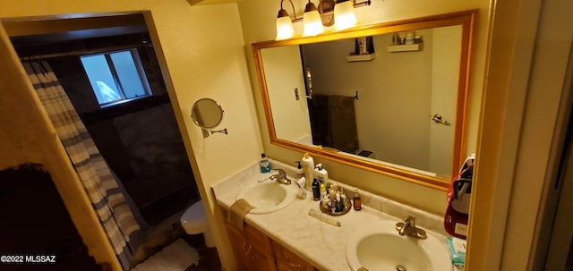 bathroom featuring a shower with shower curtain, a sink, toilet, and double vanity