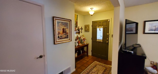 foyer with arched walkways, visible vents, a textured ceiling, and tile patterned floors