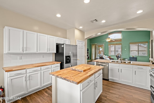 kitchen with visible vents, wood counters, appliances with stainless steel finishes, and arched walkways