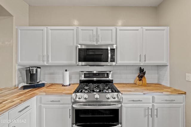 kitchen featuring butcher block countertops, white cabinetry, stainless steel appliances, and backsplash